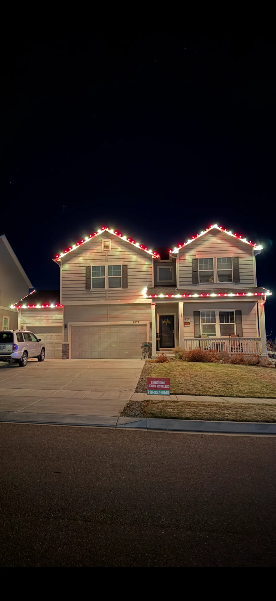 Portfolio example: red and white LED roofline and garage Christmas lights on a two-story home